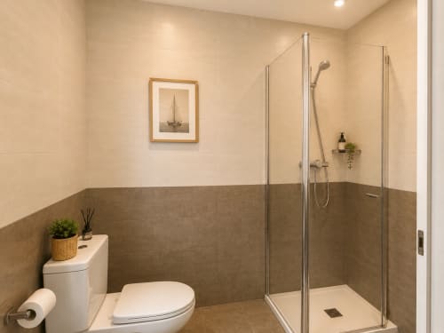 Baño moderno con ducha tipo walk-in, inodoro y azulejos beige en la casita Vila Santa Rita de Oia, Santorini