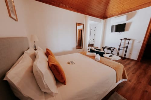 Quarto de casal luxuoso na Casa de Campo da Quinta da Pegada, Óbidos com teto de madeira, vista para o jardim, TV e comodidades modernas