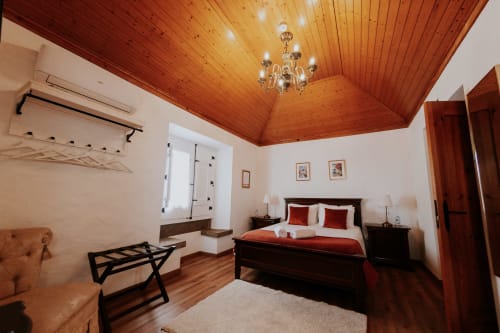 Quarto Deluxe de casal luxuoso na Casa de Campo da Quinta da Pegada em Óbidos com teto de madeira, cama em madeira escura e jardim