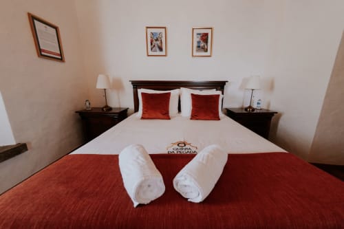 Quarto de luxo na Quinta da Pegada em Óbidos com cama de casal, detalhes em vermelho e toalhas de boas-vindas