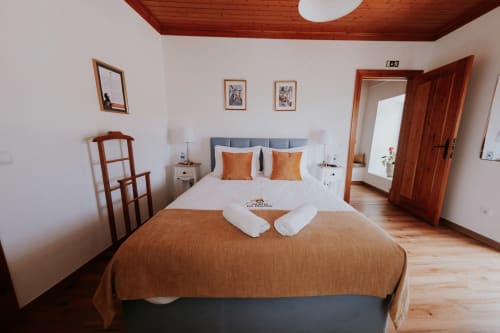 Bright bedroom with double bed, orange pillows, wooden ceiling, and garden view at Casa de Campo da Quinta da Pegada in