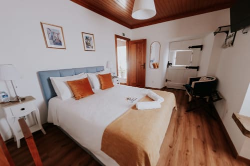 Bright double bedroom at Casa de Campo da Quinta da Pegada, Óbidos with blue headboard, white linens, orange accents and