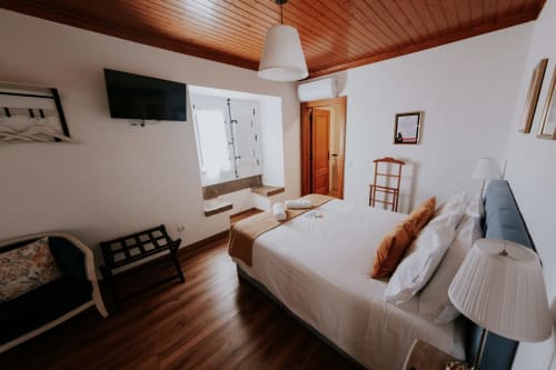 Spacious bedroom at Casa de Campo da Quinta da Pegada in Óbidos with double bed, wooden ceiling, TV, and garden view
