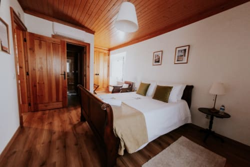 Spacious bedroom with wooden ceiling and furnishings at Casa de Campo da Quinta da Pegada in Óbidos, featuring garden views