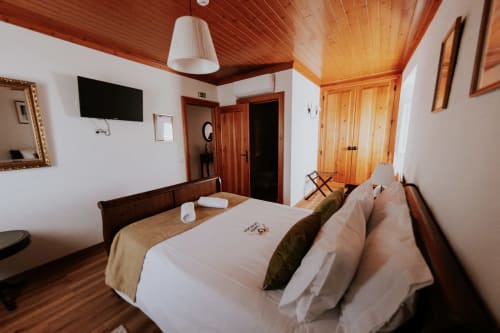 Spacious double bedroom at Casa de Campo da Quinta da Pegada in Óbidos with wooden ceiling, flat-screen TV, garden view, and