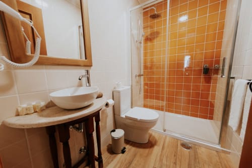 Modern bathroom at Casa de Campo da Quinta da Pegada in Óbidos with orange tile shower, vessel sink, and wood accents