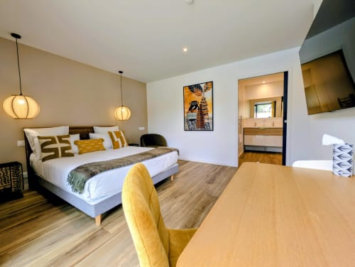 Chambre moderne à La Clairière aux Chênes à Treillières avec lit queen-size, accents jaunes, luminaires suspendus, salle de bain attenante