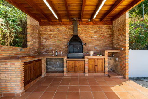 Zona de barbacoa techada con chimenea de ladrillo, muebles de madera y comedor en Ayma Villa, Alhaurín de la Torre