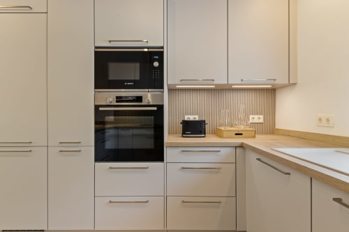 Cocina moderna con gabinetes color beige, electrodomésticos Bosch integrados, encimera de madera y backsplash en Ayma Villa Vista al