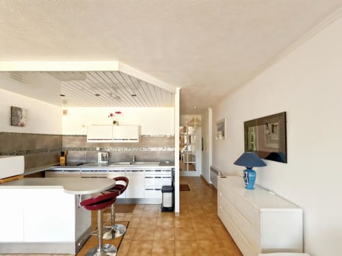 Cuisine-séjour moderne en studio à L'Île-Rousse avec mobilier blanc, bar et vue sur les montagnes