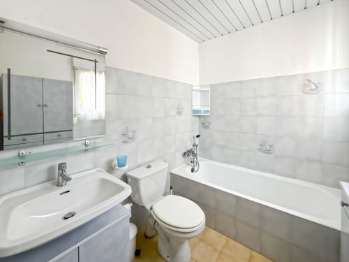 Salle de bain lumineuse du studio de L'Île-Rousse avec lavabo blanc, toilettes, baignoire et carrelage