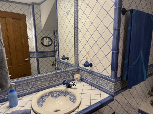 Baño azul y blanco con azulejos decorativos, lavabo redondo, espejo y toallero en el Palacio Vasco de Laukariz