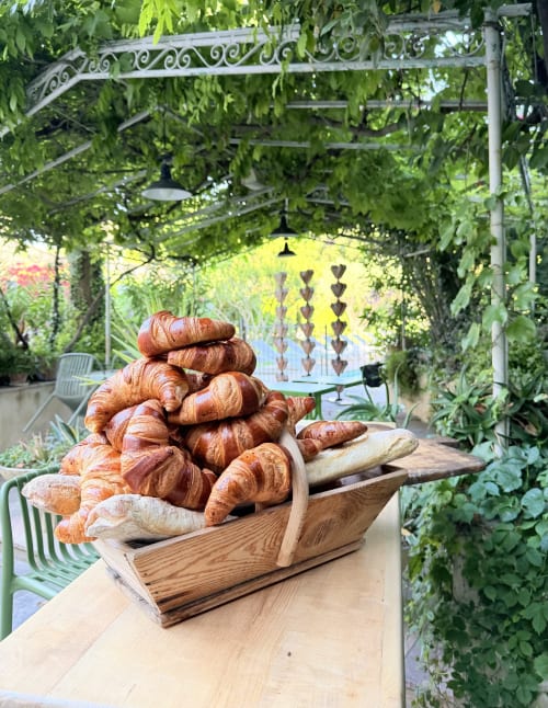 Fresh croissants and bread in wooden basket at Hôtel La Suite garden, Villeneuve-lès-Avignon
