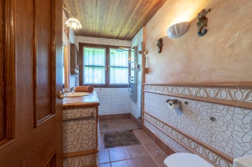 Baño elegante en la Sala Jardín del Palacio Vasco en Laukariz con mueblería de madera, ducha con azulejos blancos y pared decorativa