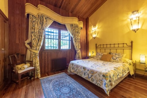 Elegante habitación del Palacio Vasco en Laukariz con vistas al jardín, muebles de madera y paredes amarillas