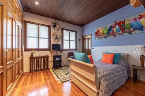 Suite Junior Birds en Basque Palace con cama de madera, coloridos cuadros de loros, pisos de madera noble y acogedora zona de estar en Laukariz