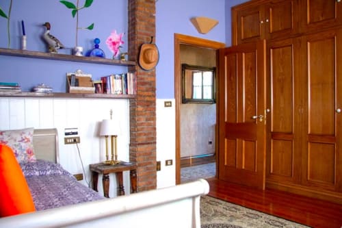Suite Junior Birds en Basque Palace con paredes moradas, armarios de madera, estanterías, chimenea y cama en Laukariz