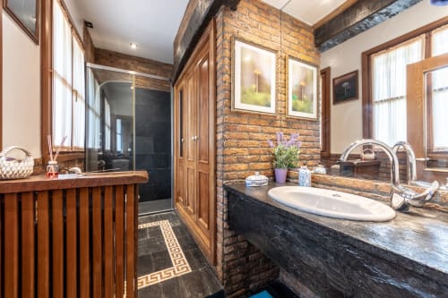 Lujoso baño de Birds Junior Suite en Basque Palace con paredes de ladrillo, lavamano de encimera oscura, ducha abierta y detalles de madera