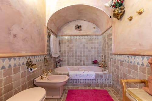 Elegante baño del Palacio Vasco con bañera, bidé rosa, azulejos mosaico y accesorios dorados en Laukariz