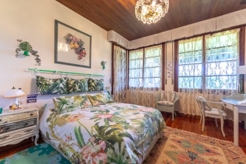 Dormitorio Green Suite en Basque Palace con ropa de cama floral tropical, techo de madera, vistas al jardín y mobiliario elegante