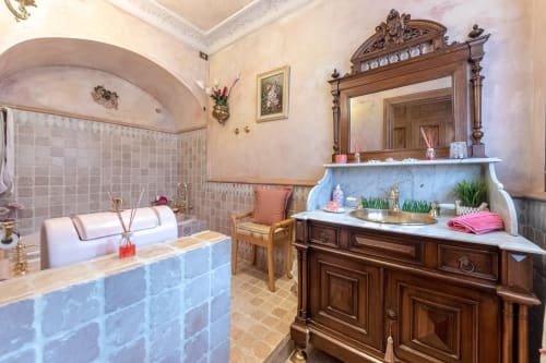 Baño elegante de la Suite Verde en Palacio Vasco con tocador de mármol, espejo de madera ornamentado y bañera de azulejos azules
