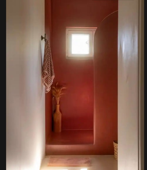 Couloir minimaliste aux murs rouge profond et fenêtre à Mas des Vignes, gîte Drôme Provence