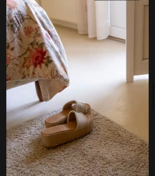 Chaussons confortables sur tapis beige au Mas des Vignes, Rochegude, avec parure de lit fleurie