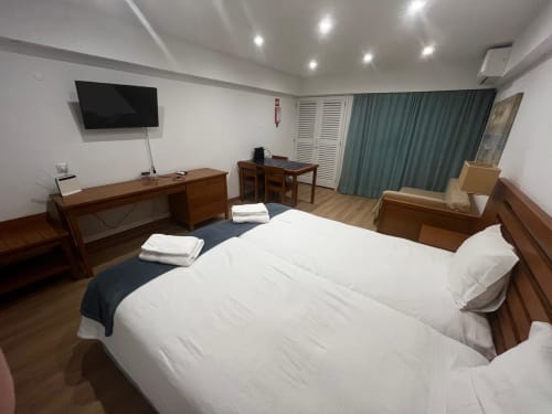 Quarto de estúdio moderno no Algarve Golden com cama de casal, TV de tela plana, móveis em madeira e cortinas verde-azulado em Cabanas
