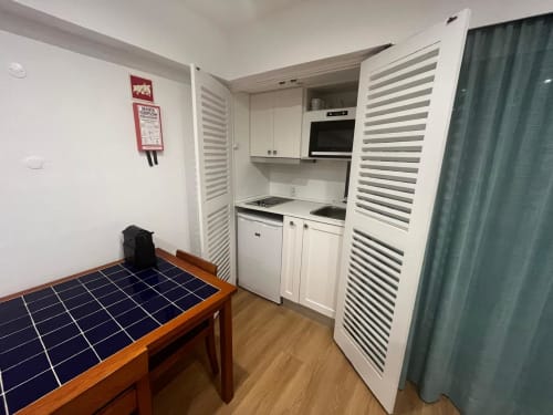 Pequena cozinha no estúdio Algarve Golden com armários brancos, fogão e forno em Cabanas de Tavira