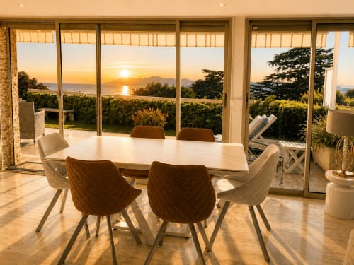 Modern dining room with sunset ocean view in Cannes villa, elegant table and chairs overlooking Mediterranean landscape