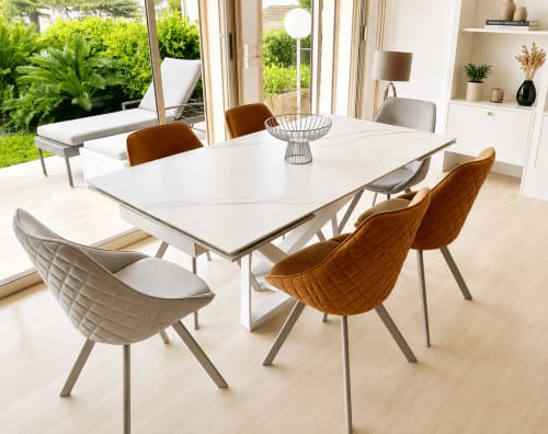 Modern dining area in Cannes with white table, brown and cream quilted chairs, garden view, and contemporary furnishings