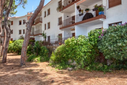 Hôtel Finques Garcia Enrich à Palafrugell avec bâtiments blancs, balcons en bois, jardins luxuriants et pins