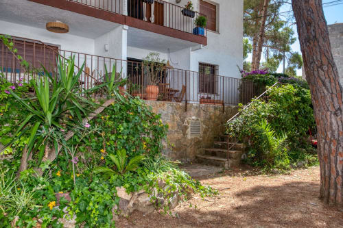 Cour luxuriante avec plantes fleuries et terrasse de l'hôtel Finques Garcia Enrich à Palafrugell, Espagne