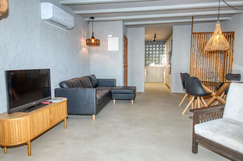 Salon ouvert et moderne chez Finques Garcia Enrich à Palafrugell avec canapé noir, mobilier bois et luminaires suspendus