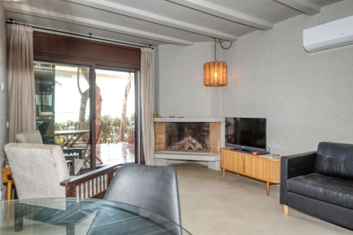Séjour moderne chez Finques Garcia Enrich à Palafrugell avec cheminée, télévision, canapé cuir et accès au balcon