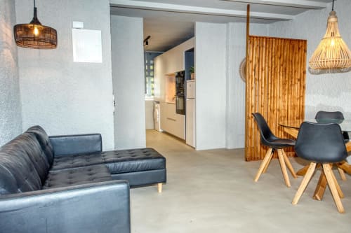 Salon moderne chez Finques Garcia Enrich : canapé anthracite, séparateurs bois et luminaires suspendus à Palafrugell