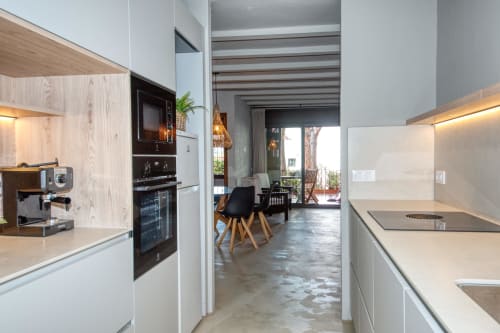 Cuisine contemporaine aux accents bois, mobilier blanc et espace de vie ouvert à Finques Garcia Enrich, Palafrugell