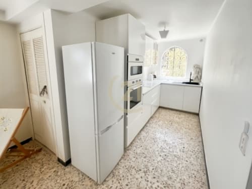 Cuisine blanche moderne avec électroménagers et sol en terrazzo, vue sur jardin dans une maison authentique à Calvi, L'Île-Rousse