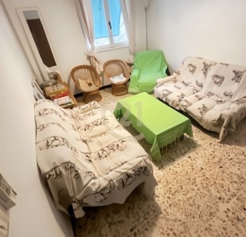 Salon chaleureux avec futons à motifs, chaises en rotin et accents verts dans un authentique appartement calvi avec vue sur jardin
