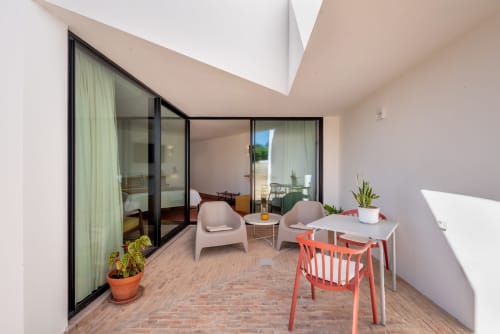 Suite Mayor balcony at Monte das Açoteias with lounge chairs, dining table, and pool view in Tavira, Portugal