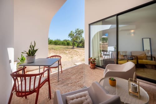 Suite Mayor terrace at Monte das Açoteias with modern seating, dining table, and rural countryside views in Tavira, Portugal