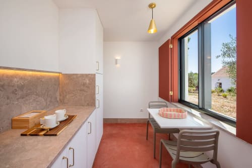 Modern suite kitchenette at Monte das Açoteias with white cabinetry, marble countertop, dining area, and large windows