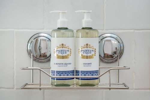 Portus Care liquid soap and shampoo bottles on chrome shelf in Monte das Açoteias bathroom