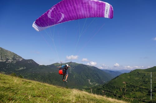 Parapentiste au parachute violet survolant les montagnes vertes de l'Ariège près de Ferrières-sur-Ariège, France