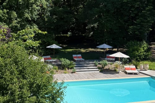 Luxury pool area at La Maison 1680 in Couches with loungers, umbrellas, and wooded gardens
