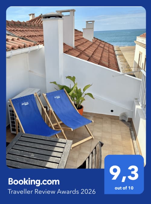Terraço Casa na Onda em Nazaré com espreguiçadeiras azuis com vista para o oceano e telhados de barro