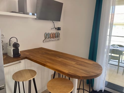 Modern kitchenette with wooden dining table and stools at Marina di Bravone beachfront apartment