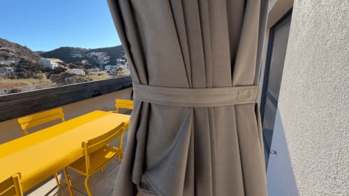 Terrasse de Bonifacio avec table à manger jaune, rideaux drapés dominant le village en montagne