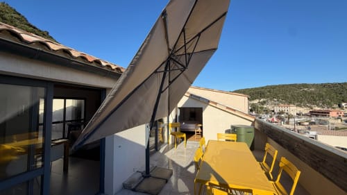 Terrasse perchée de Bonifacio avec sièges jaunes, grand parasol et vue sur les collines de Bonifacio, France