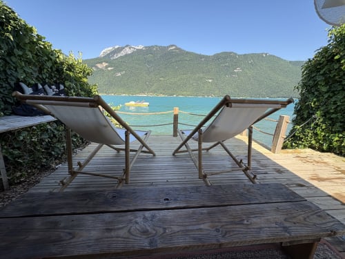 Deux transats sur terrasse en bois dominant un lac turquoise avec montagnes, au gîte de Chaparon, Lathuile
